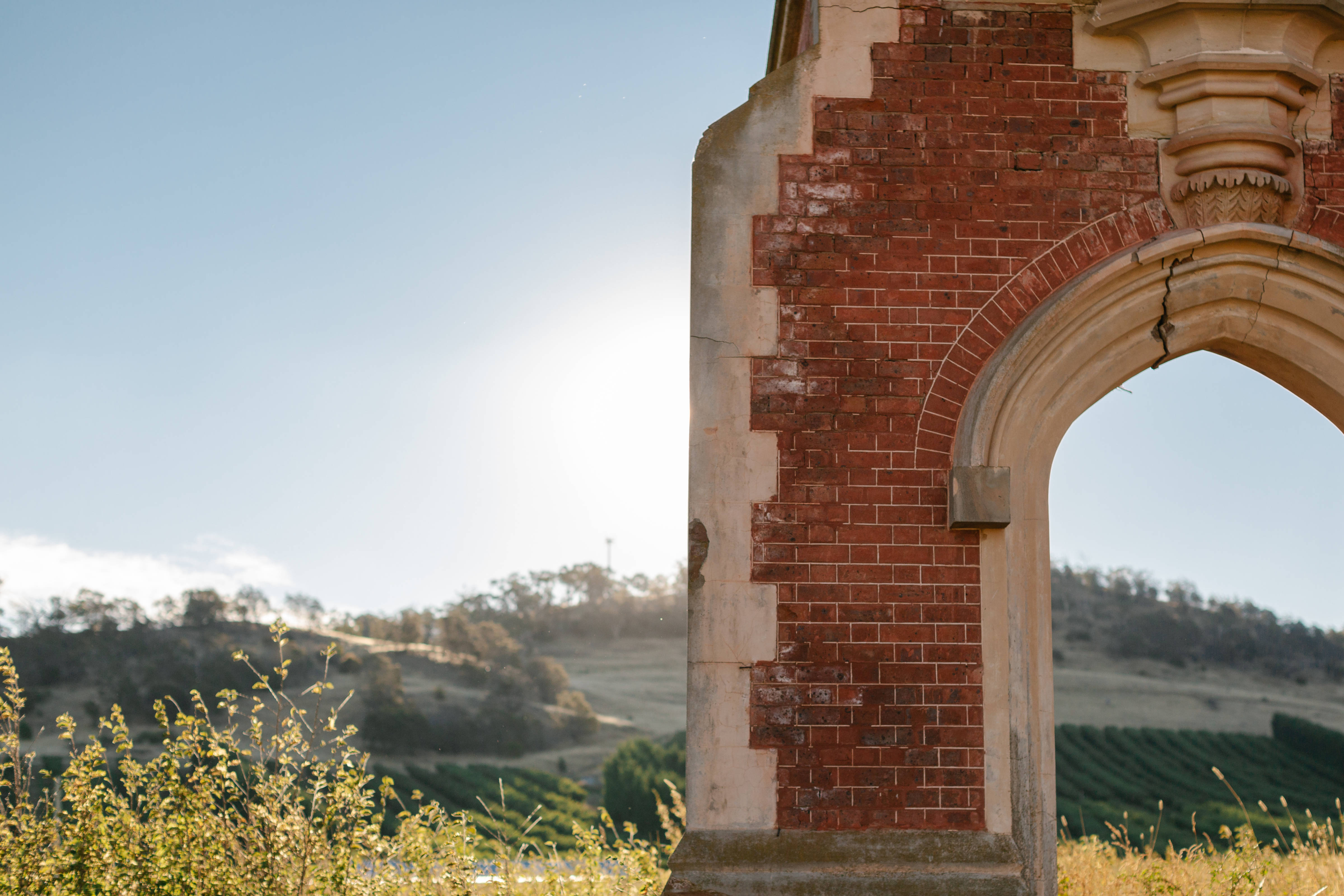 Ruin of historic red-brick doorway with including an orchard in the background. Photo: Moon Cheese Studio.